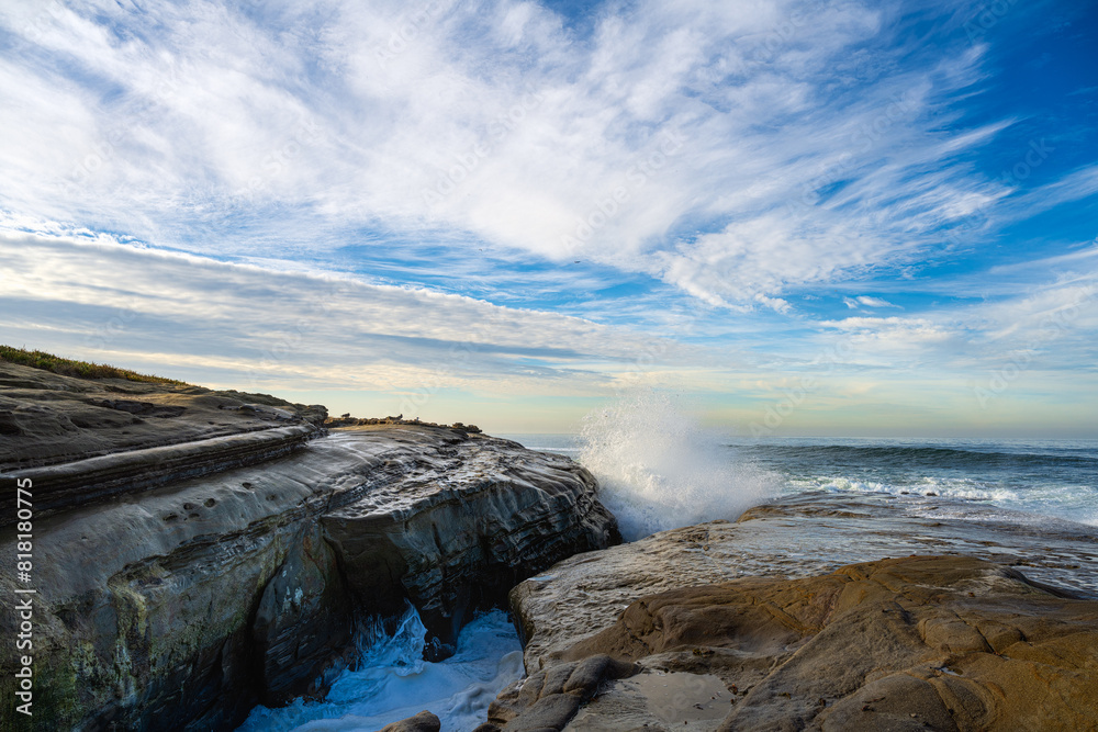  2023-12-31 ROCKY SHORELINE WITH WAVES CRASHING ON THE ROCKS PRODUCING A SPLASH OF WATER WITH A INTENSE BLUE SKY IN LA JOLLA CALIFORNIA BY SAN DIEGO