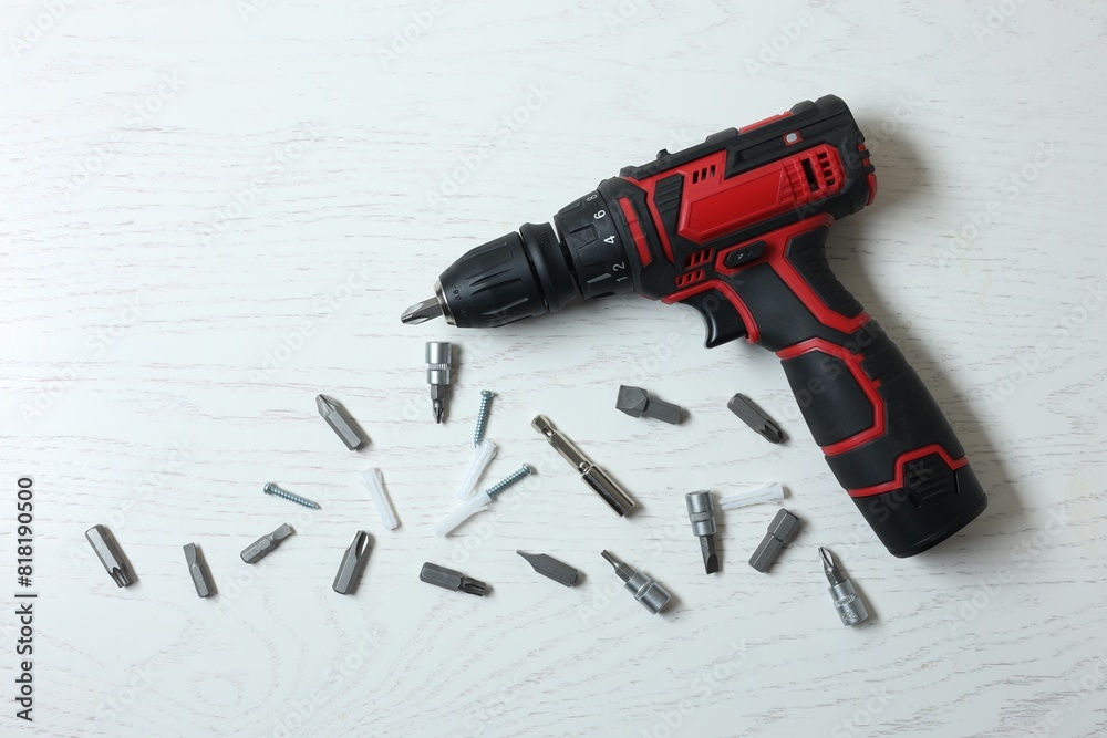 Electric screwdriver and different bits on white wooden table, flat lay Electric screwdriver and different bits on white wooden table, flat lay