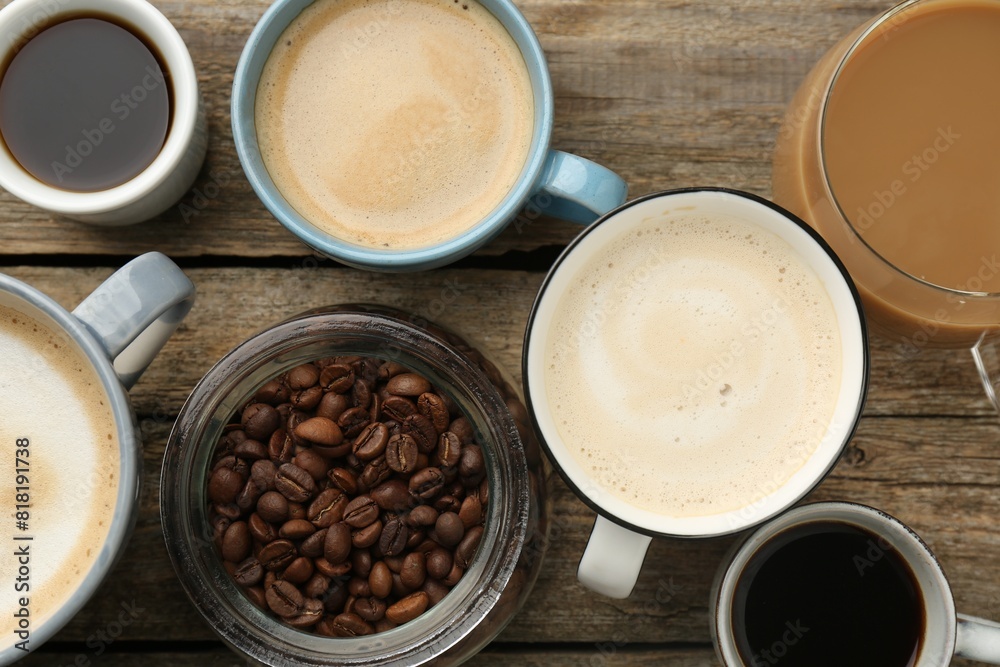 Different coffee drinks in cups and beans on wooden table, flat lay Different coffee drinks in cups and beans on wooden table, flat lay