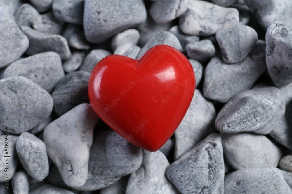 One red decorative heart on grey stones, above view One red decorative heart on grey stones, above view