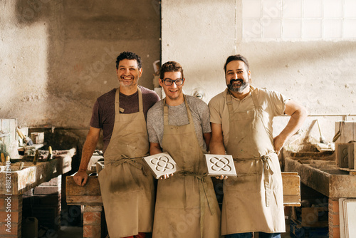 Three Smiling Men Posing With Hydraulic Tiles Featuring Barcelona Panot Pattern in a Workshop photo