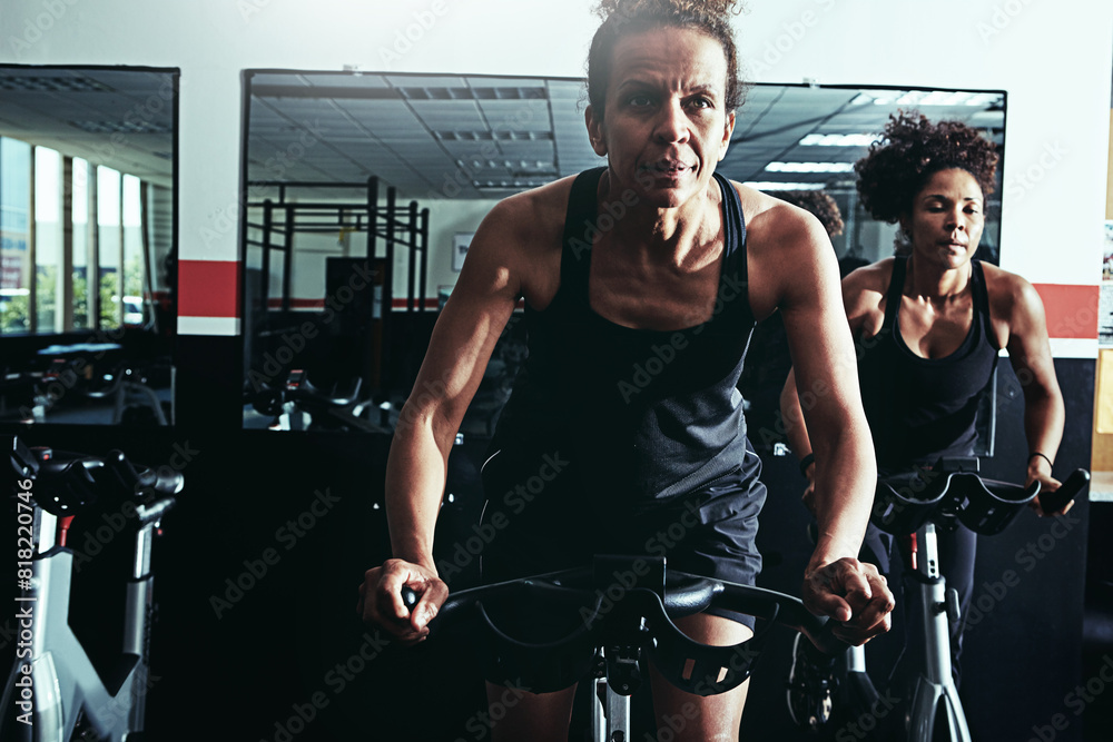 Exercise bike training and women in gym challenge or high energy with endurance progress or body workout. Wellness performance and sport with cardio healthy or cycling in spin class and fitness Stock