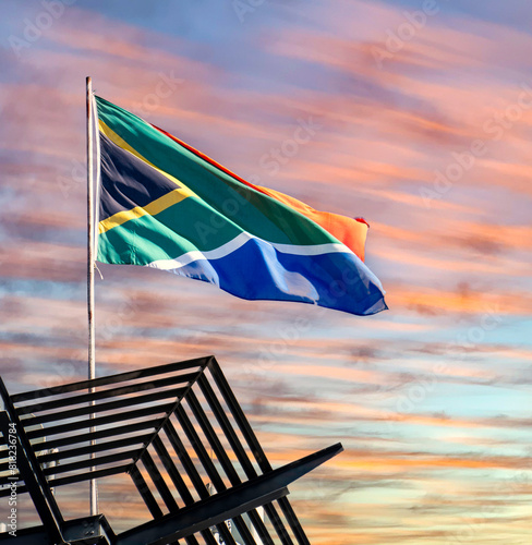The South African flag against a sunset or sunrise background.
