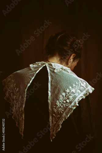 woman with embroidered collar and vintage black dress from behind in romantic attitude