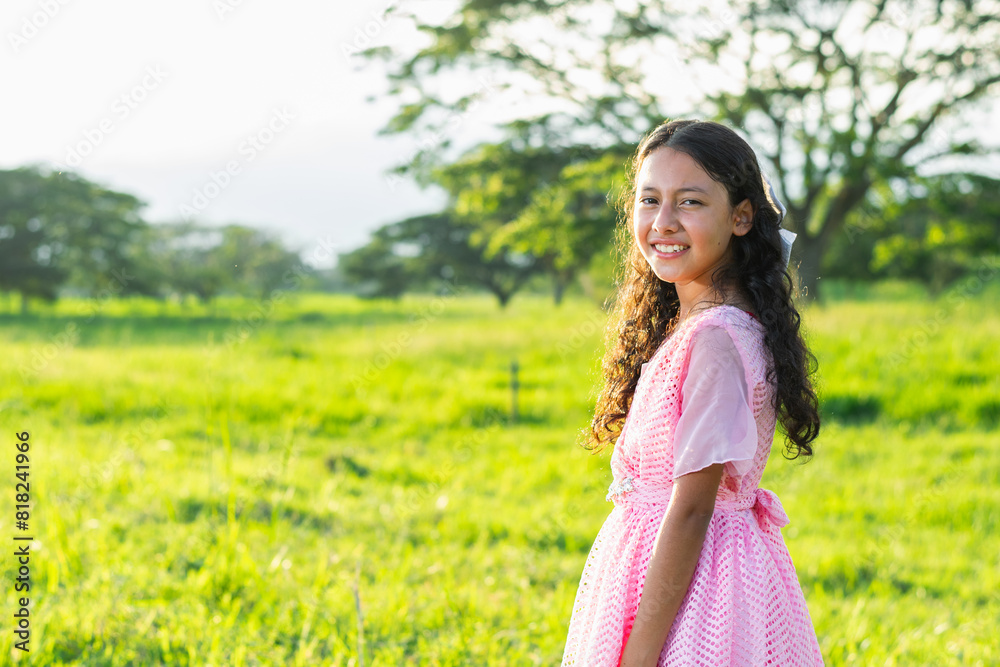 little brunette latina girl looking sideways and smiling as she walks across a grassy field little brunette latina girl looking sideways and smiling as she walks across a grassy field