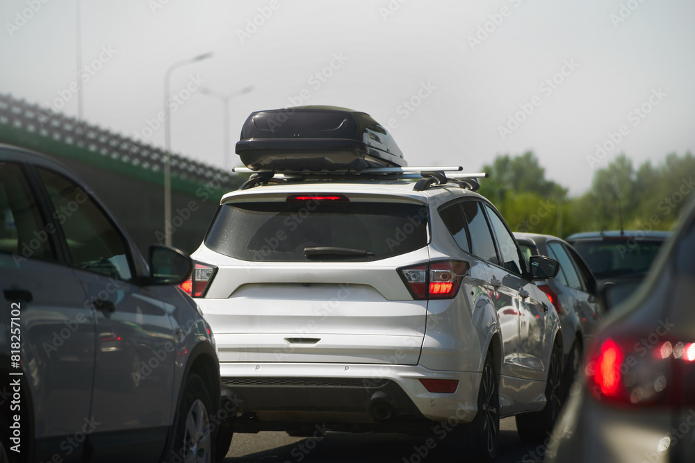 White suv equipped with a rooftop cargo carrier amidst heavy traffic on a sunny day White suv equipped with a rooftop cargo carrier amidst heavy traffic on a sunny day