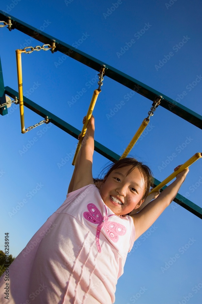 Fototapeta premium A Young Girl Hanging From Bar