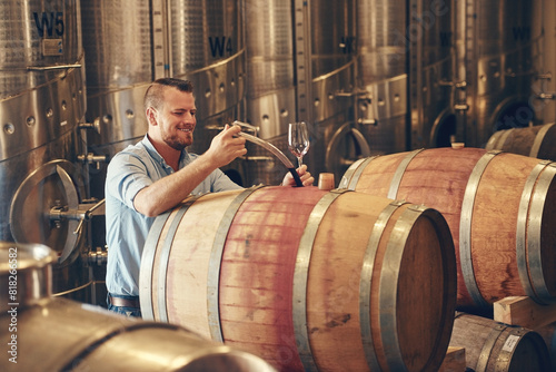 Man, barrel and wine maker with glass as manager for tasting, process and production. Supplier, winery and happy or smile at product for alcohol manufacturing, craft and liquor at factory in startup photo