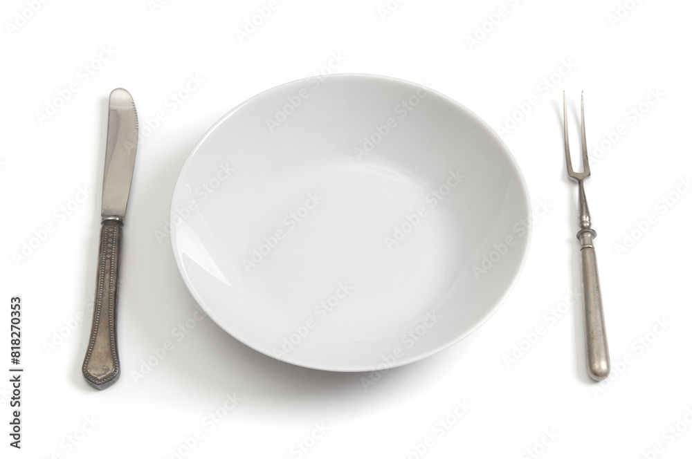 Empty plate with antique fork and table-knife on a white background
