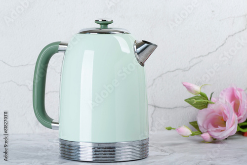 A green electric kettle and roses on the kitchen table.