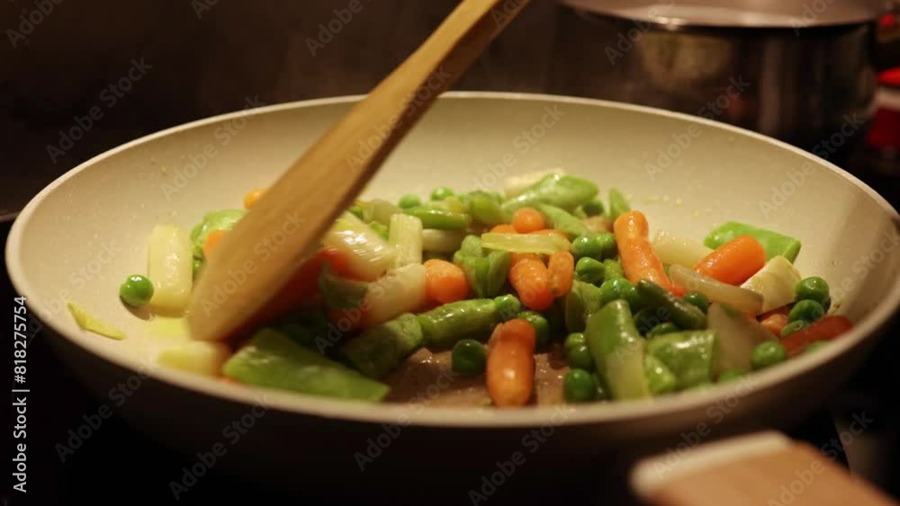 Mix Of Different Vegetables Fried In A Hot Frying Pan. Green peas, asparagus, carrots. Housewife is cooking gourmet meal in the kitchen at home. Mix Of Different Vegetables Fried In A Hot Frying Pan. Green peas, asparagus, carrots. Housewife is cooking gourmet meal in the kitchen at home.
