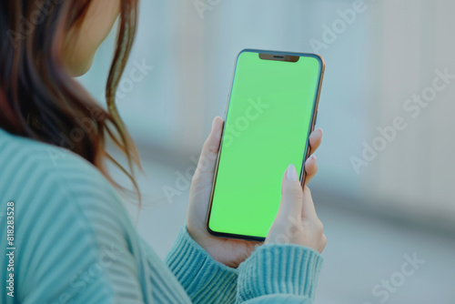 A woman is holding a green iPhone. The phone is turned off and the screen is green. The woman is looking at the phone with a smile on her face photo