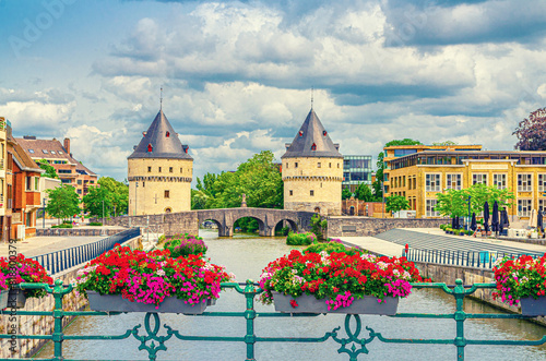 Kortrijk cityscape with Lys river, Broel Towers Gothic style buildings and Bridge in historical centre, red flowers on bridge fence, Fortification towers, belgium landmark, Flemish Region, Belgium photo