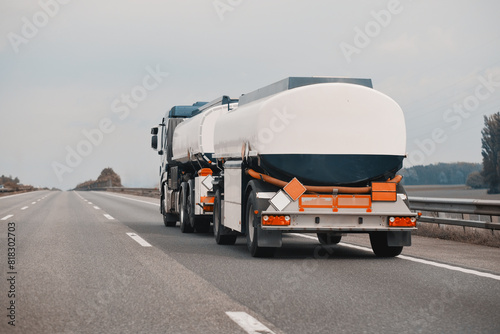 Petrol truck on highway hauling fossil oil refinery products. Fuel delivery transportation. Aviation fuel transportation. Compressed gas carrier truck rear view on a highway. Dairy products carrier.