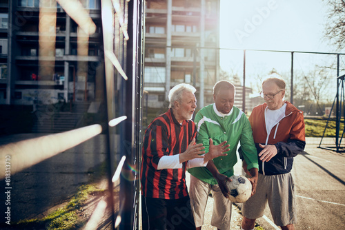 Senior friends playing soccer together in a park photo