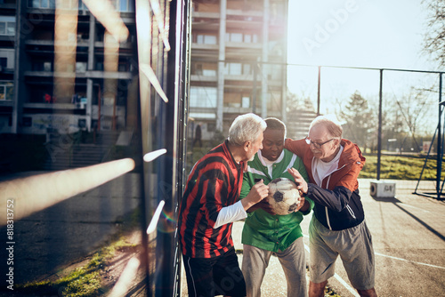 Senior friends playing soccer together in a park photo