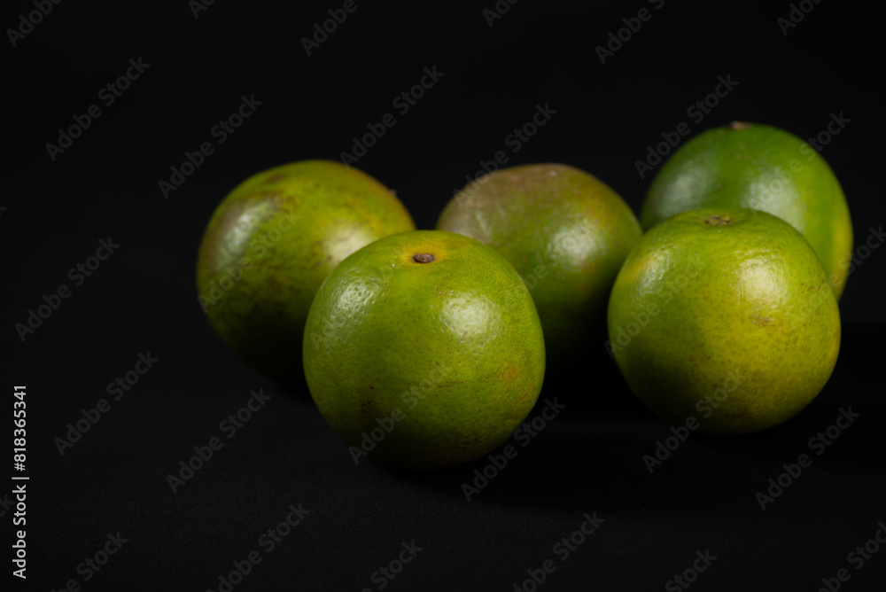 Group of still green oranges on a black background. Group of still green oranges on a black background.