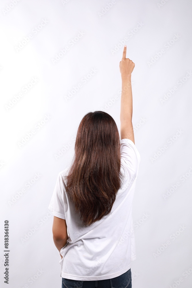 Fototapeta premium Rear view of young asian woman with long hair pointing above. Isolated on white background.