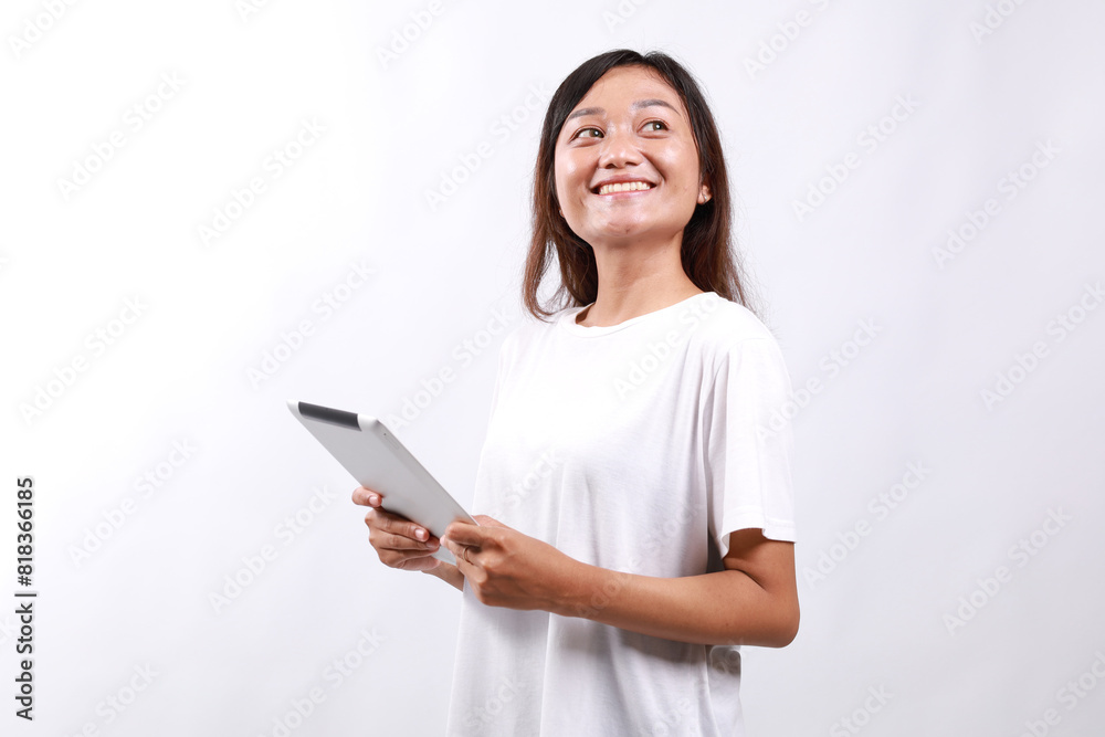 Smiling young asian college student woman using tablet computer, happy student woman in casual looking empty space standing over white background Smiling young asian college student woman using tablet computer, happy student woman in casual looking empty space standing over white background