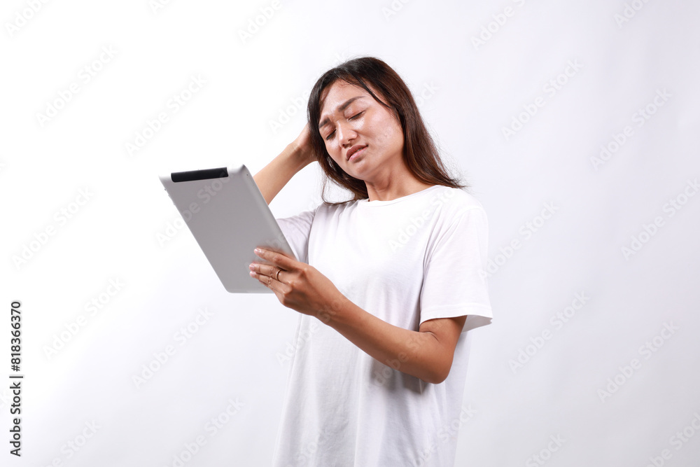 Attractive young asian woman holding a digital tablet while standing over white background with confused face expression Attractive young asian woman holding a digital tablet while standing over white background with confused face expression