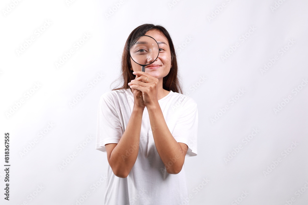 Asian woman detective looking through magnifying glass with intrigued look, found clues, standing over white background Asian woman detective looking through magnifying glass with intrigued look, found clues, standing over white background