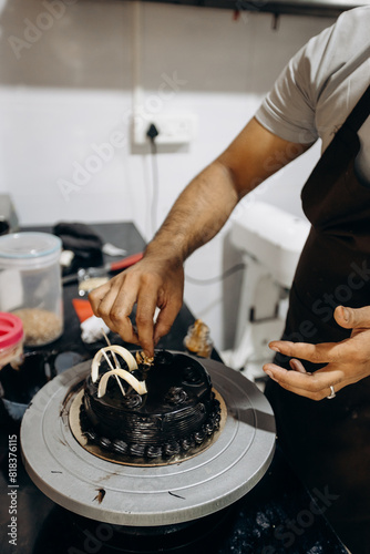 Unrecognizable male chef decorates candied chocolate cake. Small business entrepreneurship. 