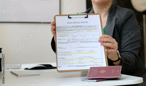 Close up of a woman holding a visa application paper document with a German passport laying on office table photo