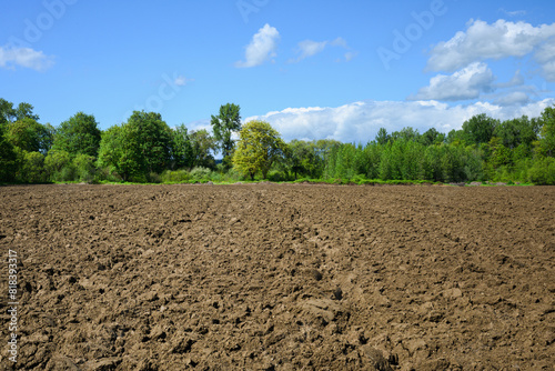 Agricultural farm field plowed ready for spring planting with brown soil under blue ky 