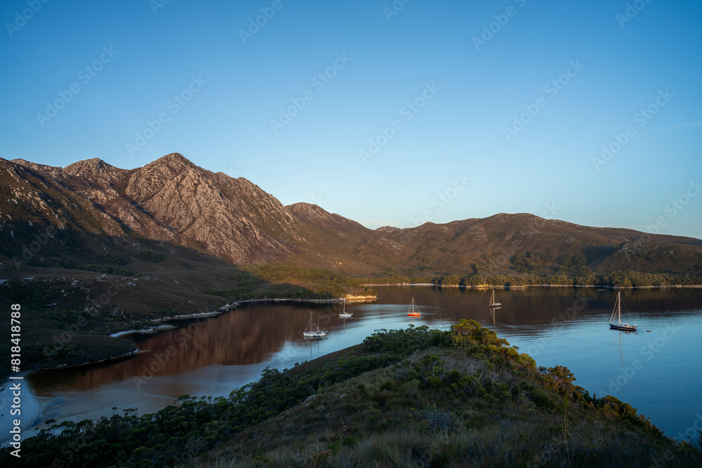 Fototapeta premium World heritage port davey national park in tasmania Australia, with mountains and river. boats in a bay in the evening