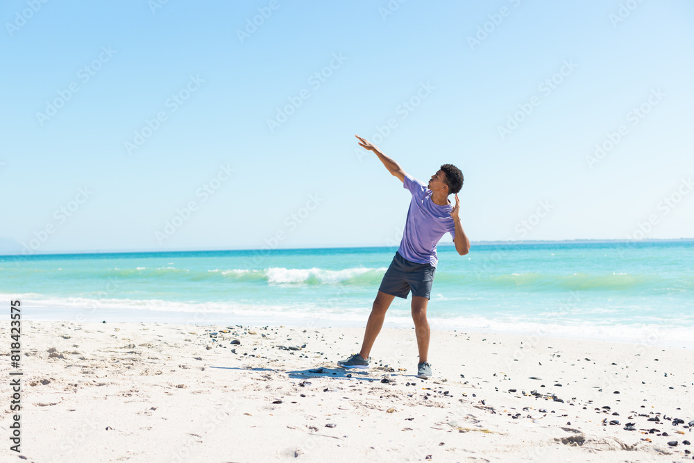 At beach, biracial young man throwing frisbee, wearing purple shirt At beach, biracial young man throwing frisbee, wearing purple shirt