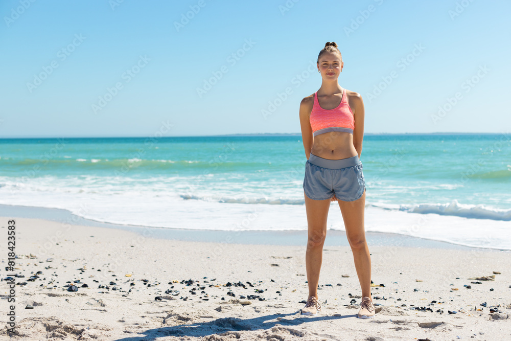 At beach, Caucasian young woman standing, hands on hips At beach, Caucasian young woman standing, hands on hips