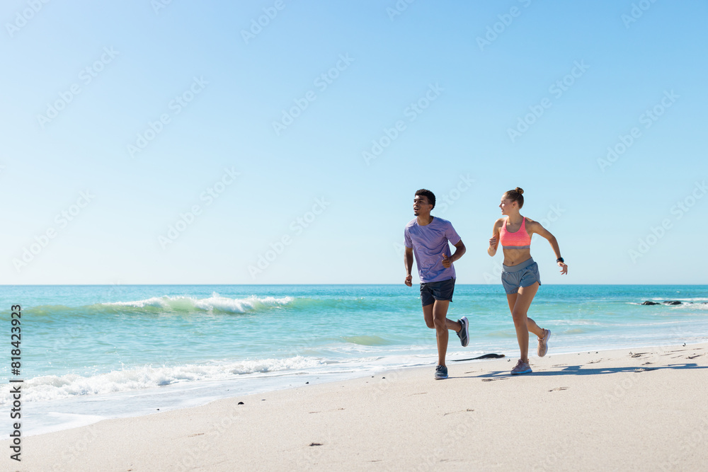 At beach, diverse couple running, enjoying time together At beach, diverse couple running, enjoying time together