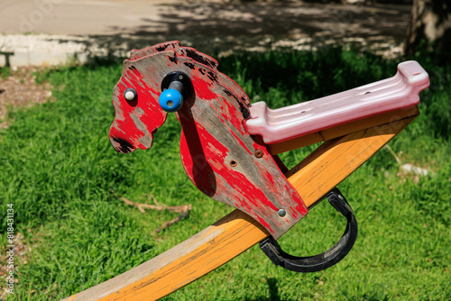 A wooden horse with a blue and black head is sitting on a wooden plank