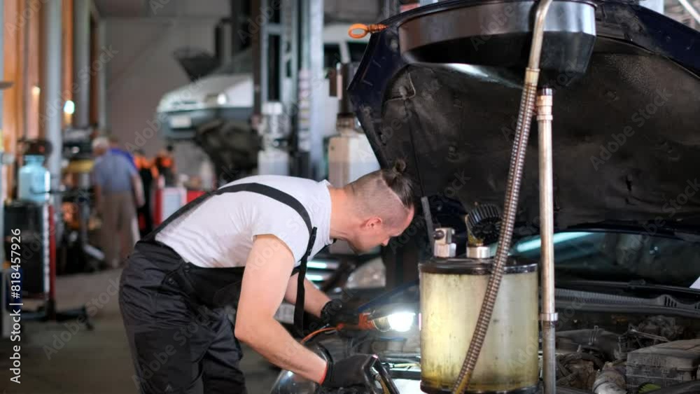 A mechanic is working on a car in a garage with the hood open A mechanic is working on a car in a garage with the hood open