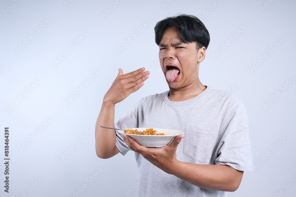 Young Asian Guy Eat Spicy Hot Noodle While Sticking Tongue Out Isolated On White Background Young Asian Guy Eat Spicy Hot Noodle While Sticking Tongue Out Isolated On White Background