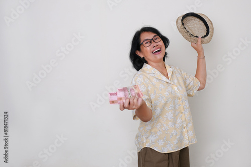 Woman standing and looking excited holding some cash money and a summer hat on left hand photo