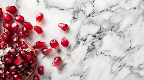 Pomegranate seeds scattered on a beautiful marble surface, offering a contrast between the vibrant red and elegant marbled texture. © kittikunfoto