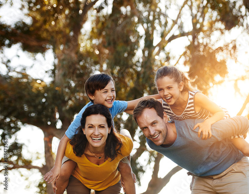 Portrait, happy family and piggyback children at park for love, care or bonding together in nature. Mother, father and carry kids at garden for game, support and parents laughing on summer holiday