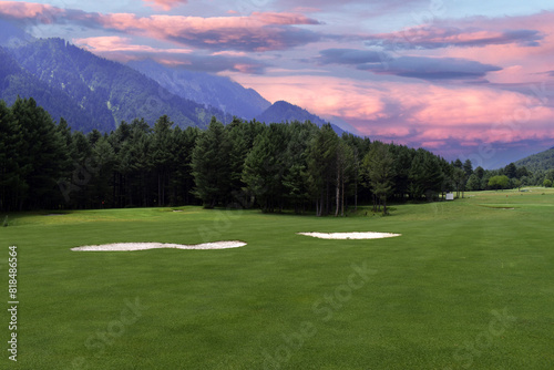 A beautiful view of lush green golf course surrounded by beautiful hills with pine trees at Pahalgam Kashmir India.