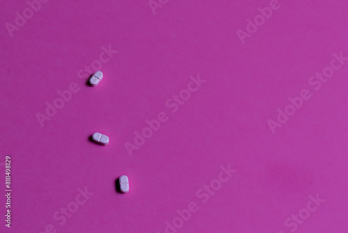 Three pink pills on a bright pink background.