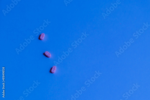 Three pink pills on a bright blue background.