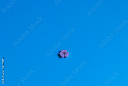 Three pink pills forming a triangle on a bright blue background.