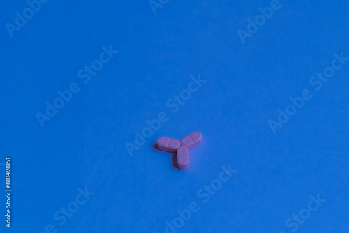 Three pink pills forming a star on a bright blue background.