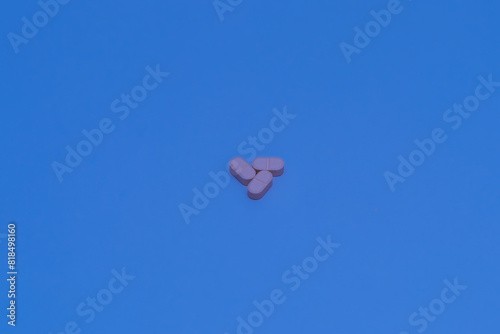 Three pink pills forming a star on a bright blue background.