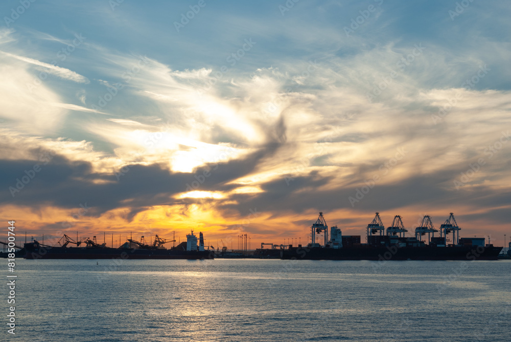 The sun sets over the industrial port area of Vancouver BC as viewed from a BC Ferry