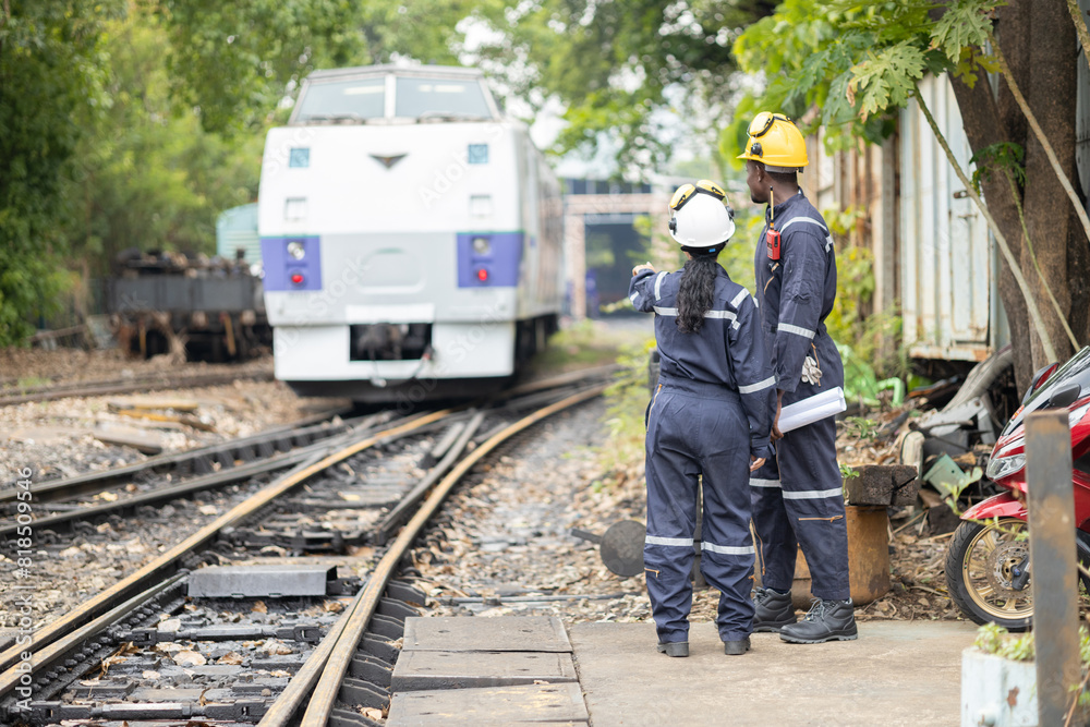 Fototapeta premium Railway Workers Discussing Plans on Railroad Track