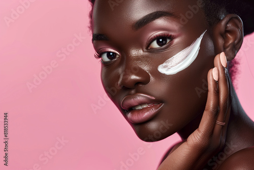 A woman with dark skin is applying makeup to her face. She is wearing a pink background. Concept of beauty and self-care, as the woman takes the time to enhance her appearance