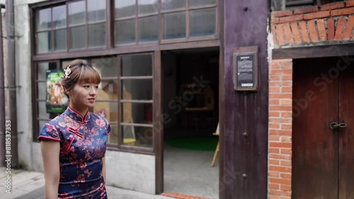 Young Taiwanese woman in blue floral cheongsam dress walking along arched colonnade in Bopiliao Old Street, Wanhua District, Taipei City. Slow-motion photo