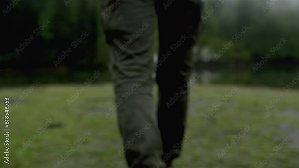 Tourist man standing on grass and looks at foggy lake landscape in woods. Traveling alone, weekend activity, nature concept 