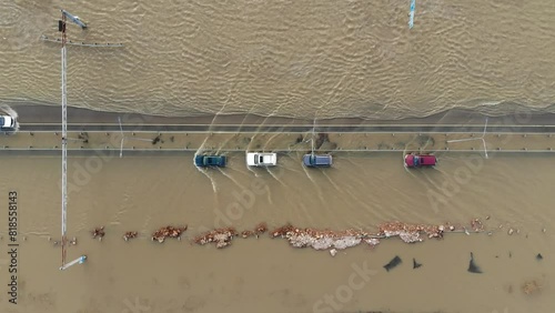 cars and trucks driving along a flooded highway during floods and floods after rains and snow melt water filmed from a drone